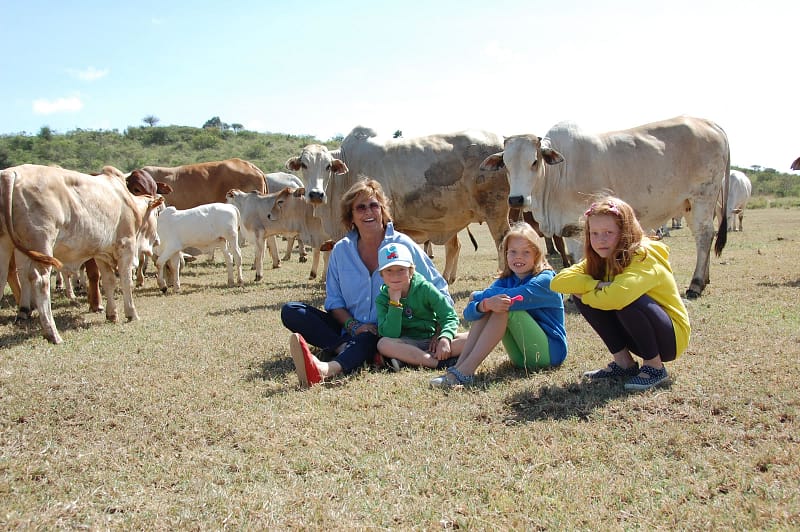 Family sat in front of a herd of Boran cattle